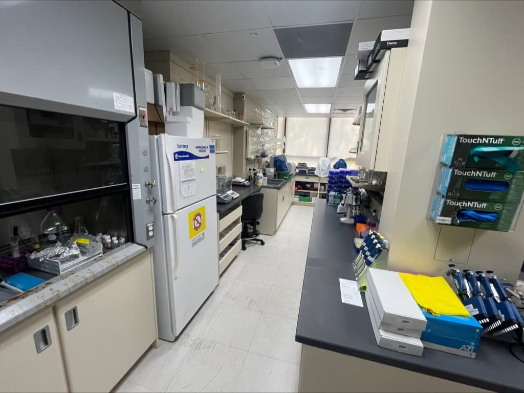 Laboratory aisle with fume hood, refrigerator, and pipette stations